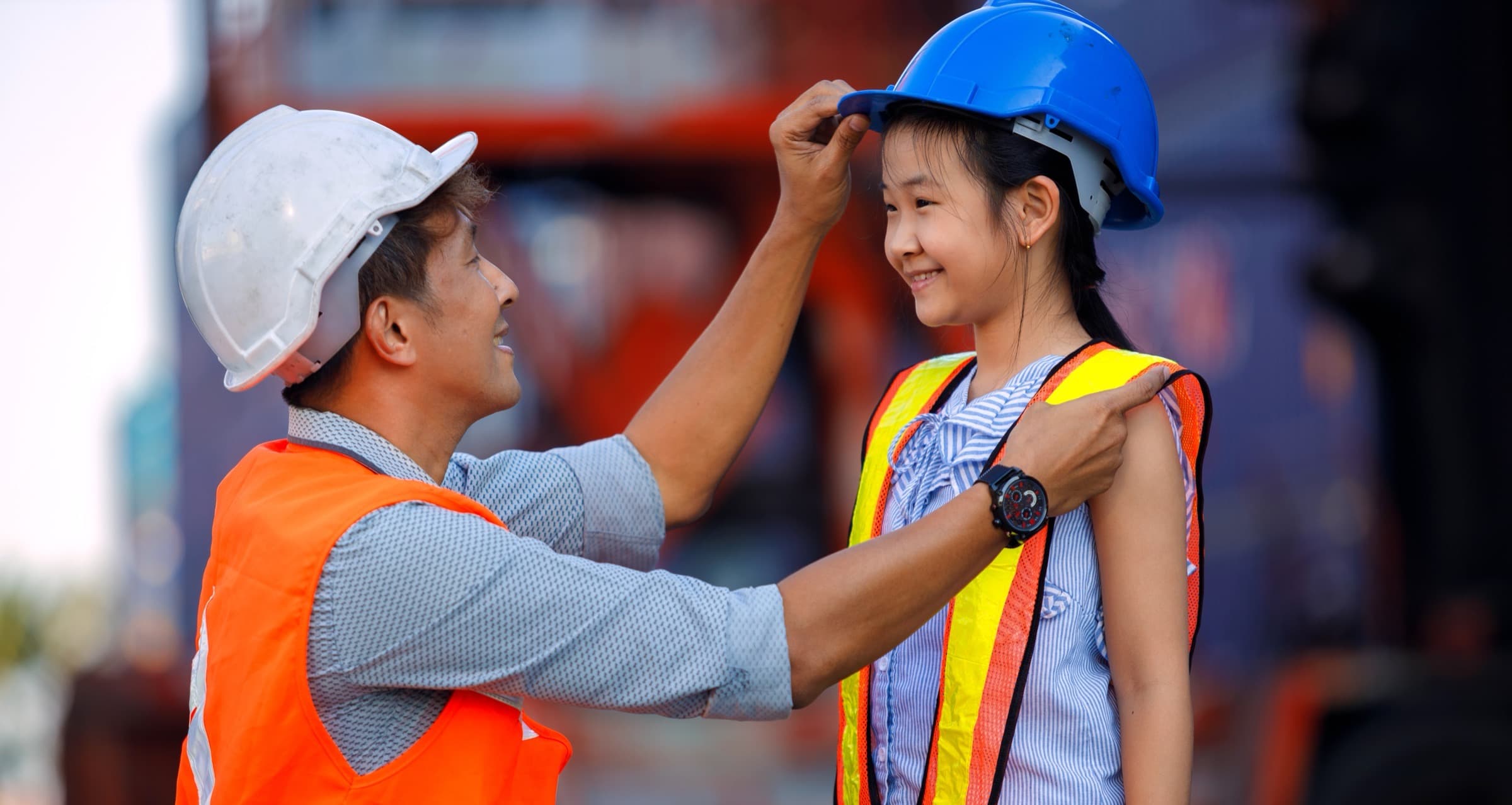 A dock worker fitting a safety helmet on a child